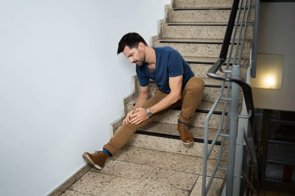Man Sitting On Staircase After Slip And Fall Accident